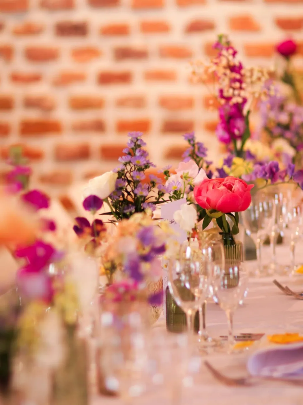 Image d'inspiration : fleurs des champs sur une table de fête, mur de briques